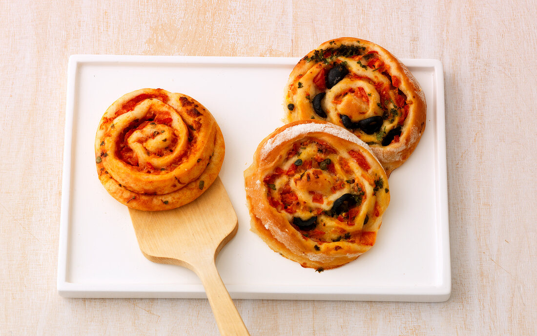 Two kinds of pizza pinwheels with spatula on platter