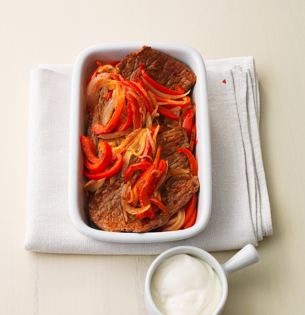 Beef steaks with an onion and pepper medley in a baking dish