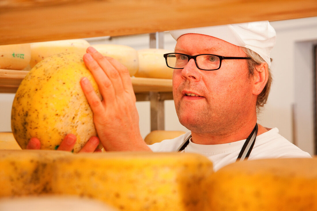 Close-up of man checking cheese on the shelf