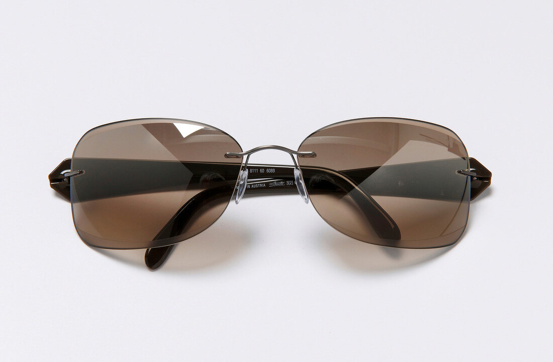 Close-up of ultra-lightweight sunglasses with dark brown ironing on white background