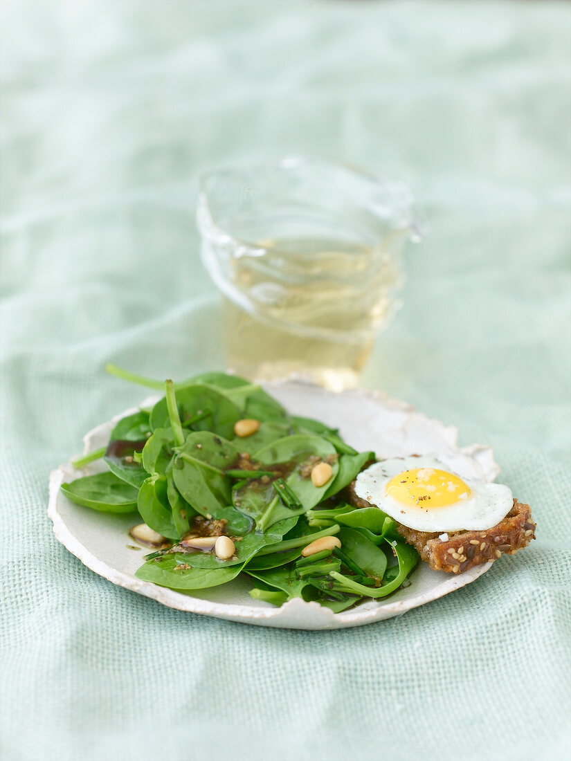 Spinach salad with quail egg crostini on plate