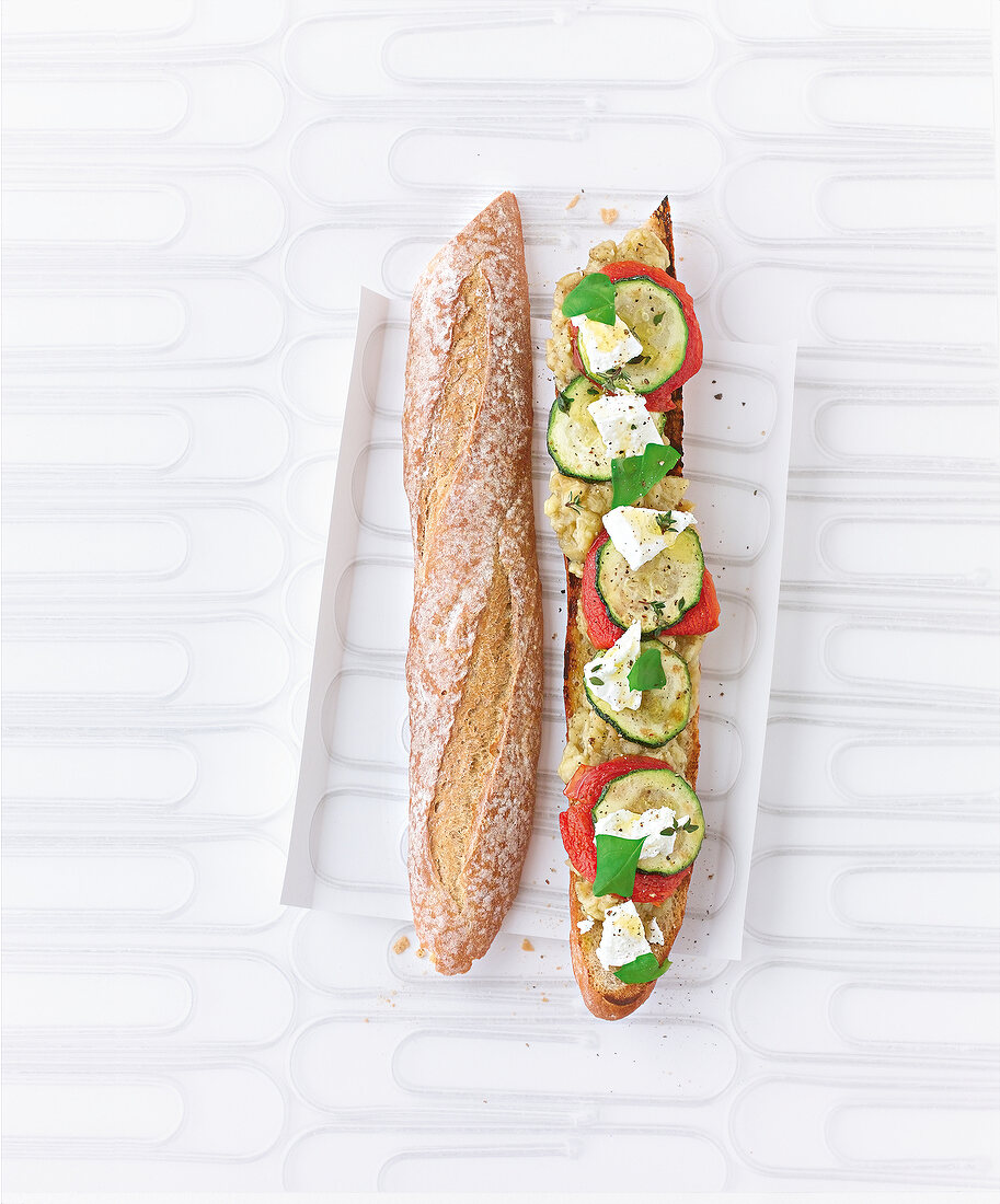 Baguette garnished with eggplant caviar, goat cheese and zucchini on tray