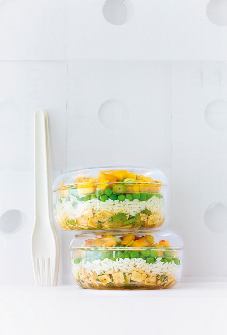 Rice salad with mango and tofu in transparent box kept on table