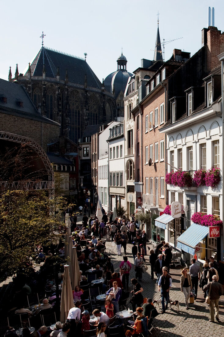 People at cafe and walking on street, Cathedral church on background, Aachen, Germany