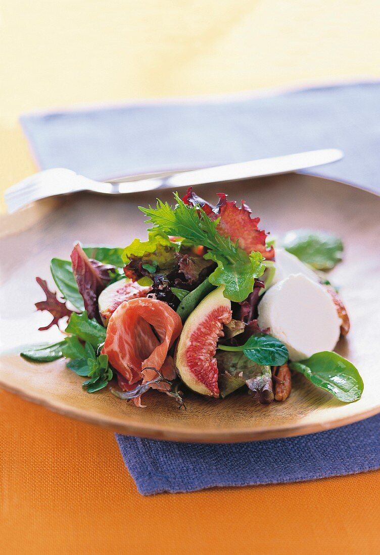 Arugula salad with figs, parma ham and fresh goat cheese on plate