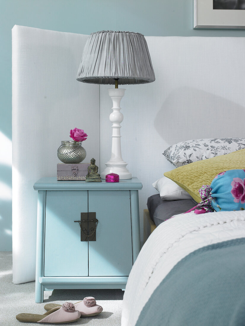 Lamp shade with pleated fabric and Asian styled dresser next to bed