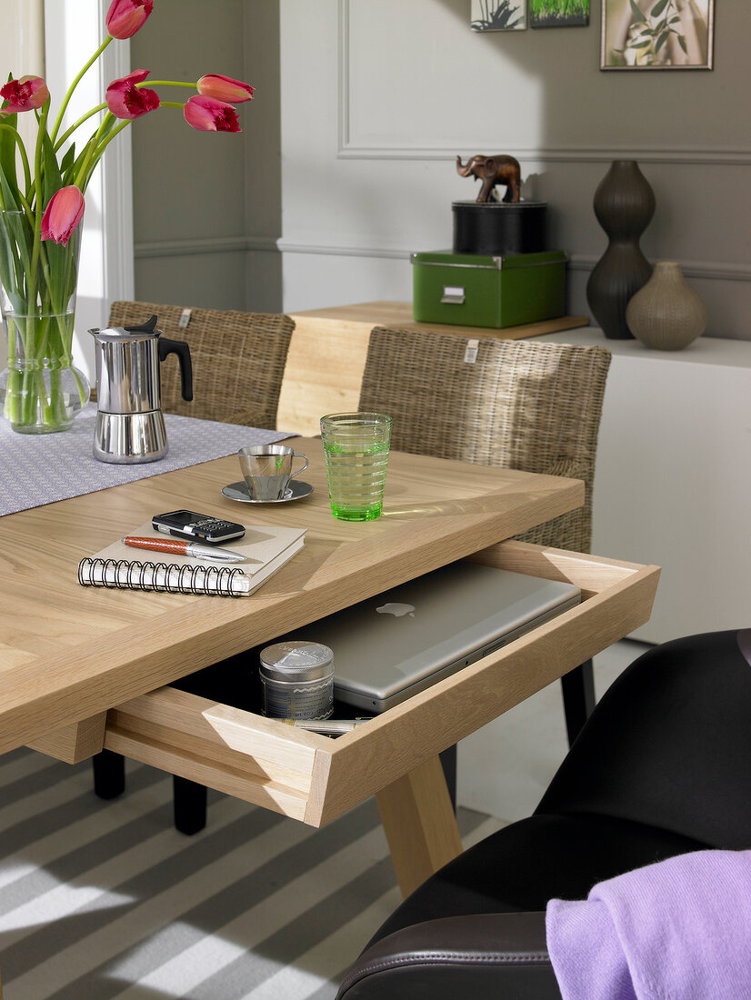 Wooden dining table with drawer, laptop and work documents