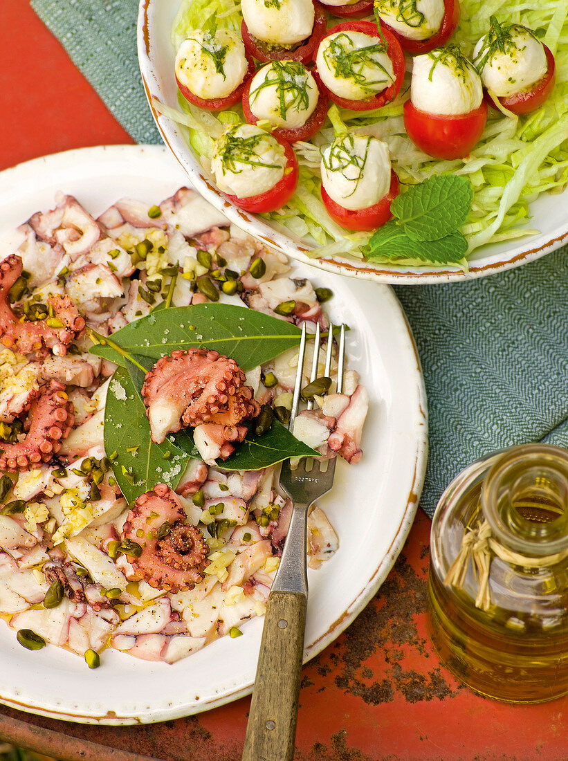 Stuffed cherry tomatoes and octopus carpaccio on plates