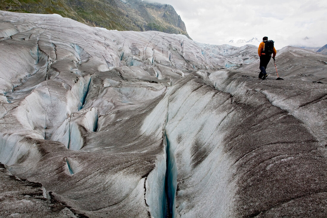 Hiker in front of ice wall in Aletsch Glacier, Marjelesee, Valais, Switzerland