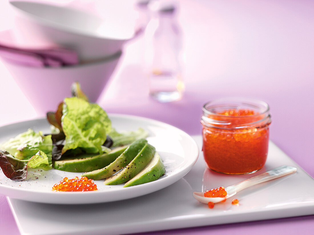 Fresh salad on plate with caviar in small glass jar