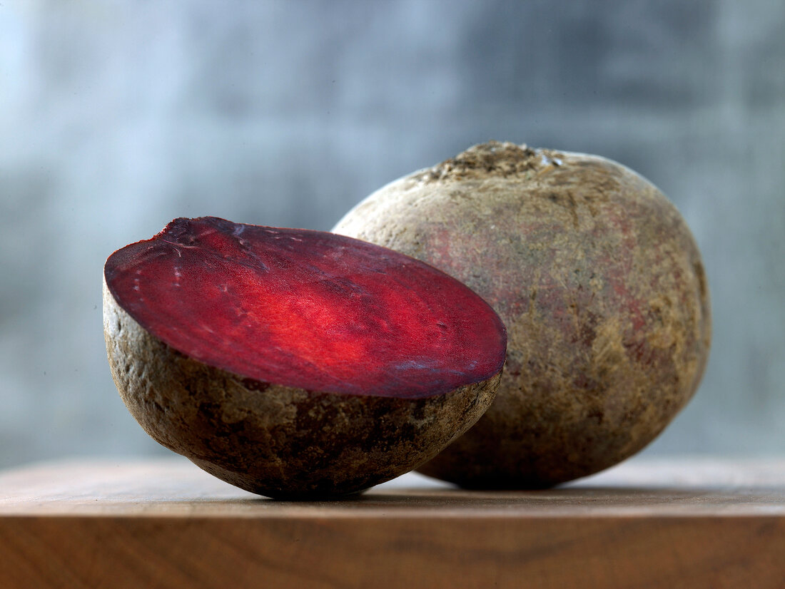 Close-up of whole and halved beetroot on wooden surface