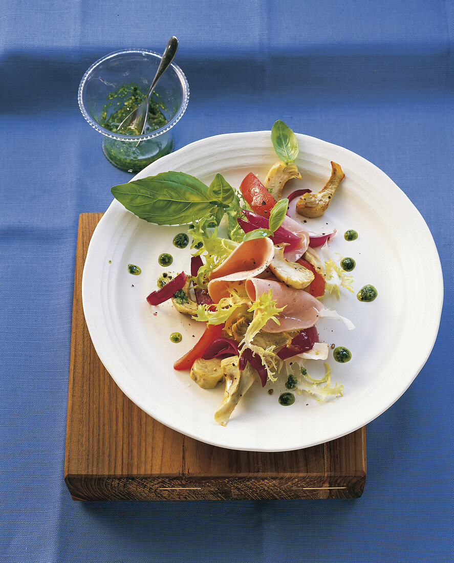 Sausage salad with pesto and artichoke on plate