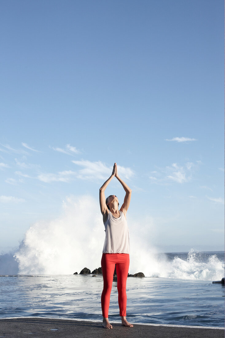 Brunette woman performing sukshma yoga exercise on beach