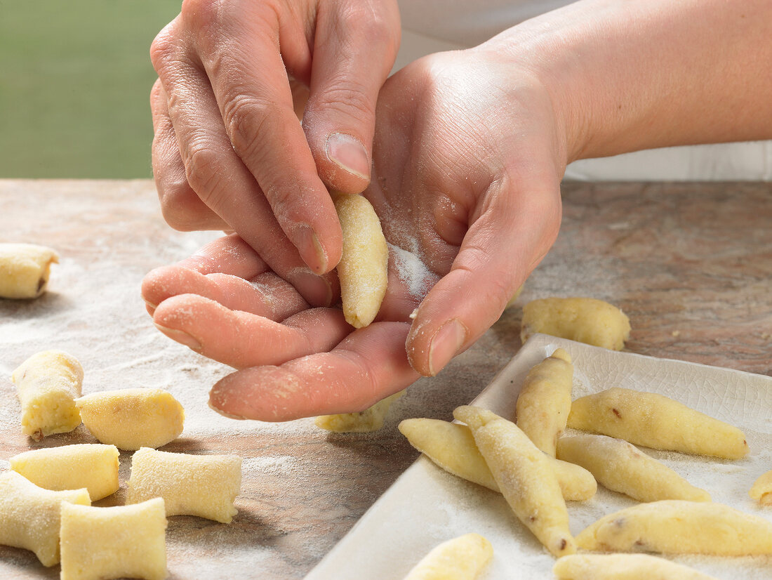 Close-up of hands rolling pieces of dough, step 3