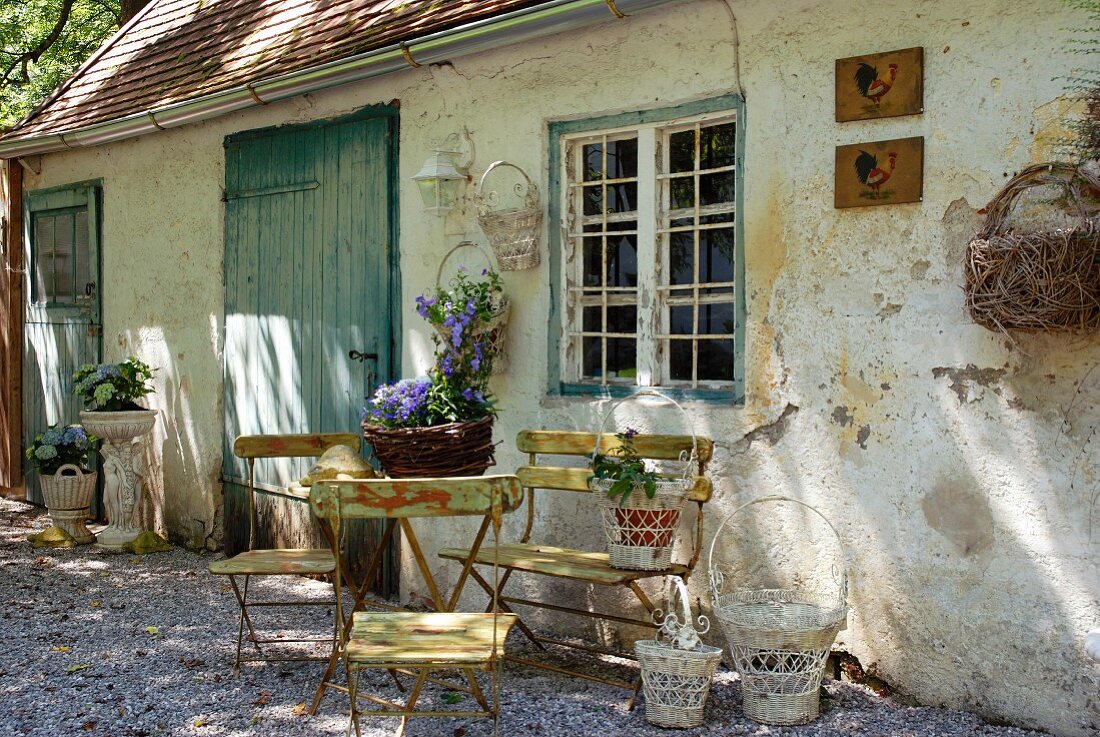 Retro garden furniture in front of a house with a flaking facade