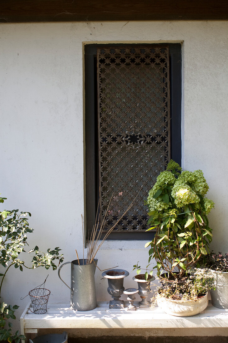 Small garden window with grid, plant pots and various metal objects