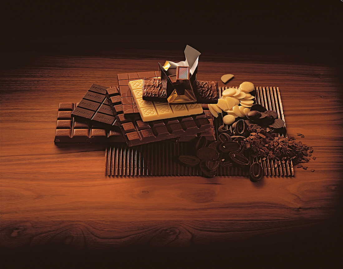 Variety of chocolate bars and chocolate flakes on wooden surface