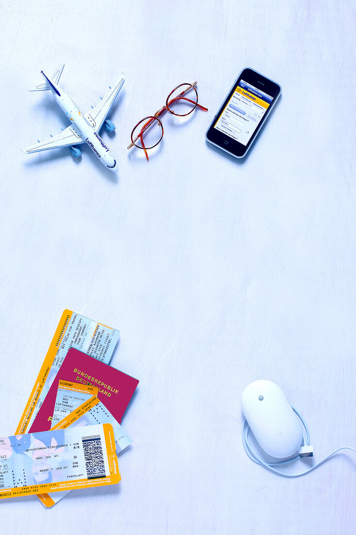 Aircraft model, mobile, glasses, computer mouse and travel documents on white background