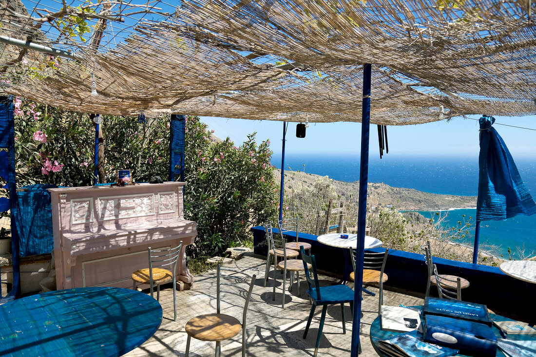 Pink piano and set table on terrace tavern overlooking sea in Livanian, Crete, Greece