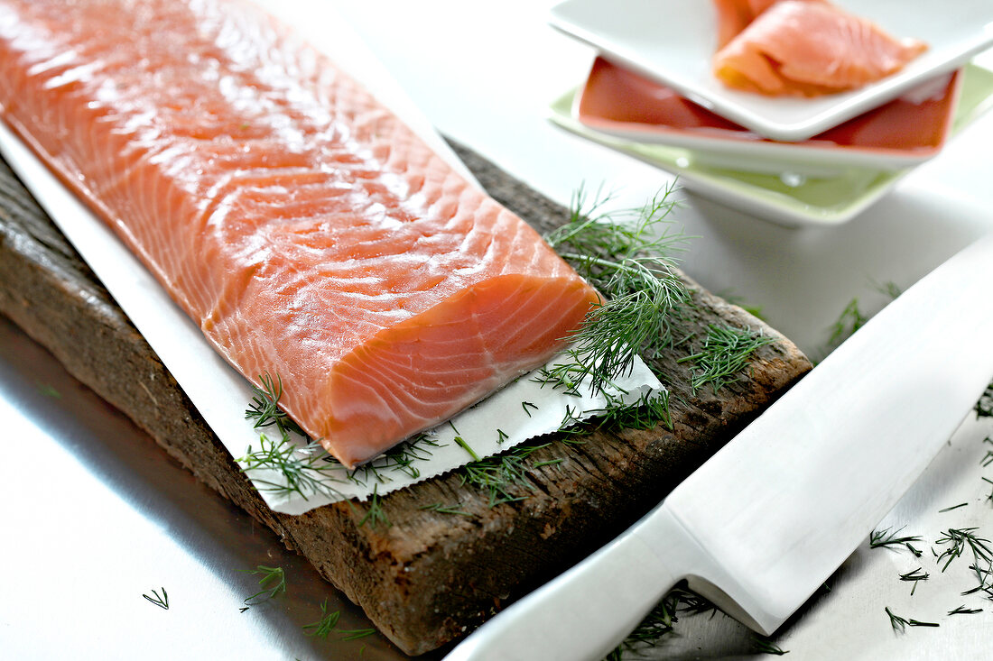 Salmon with herbs on wooden board with knife
