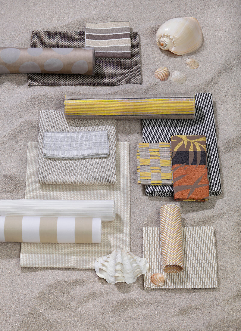 Different types of patterned fabrics and shells on sand at beach