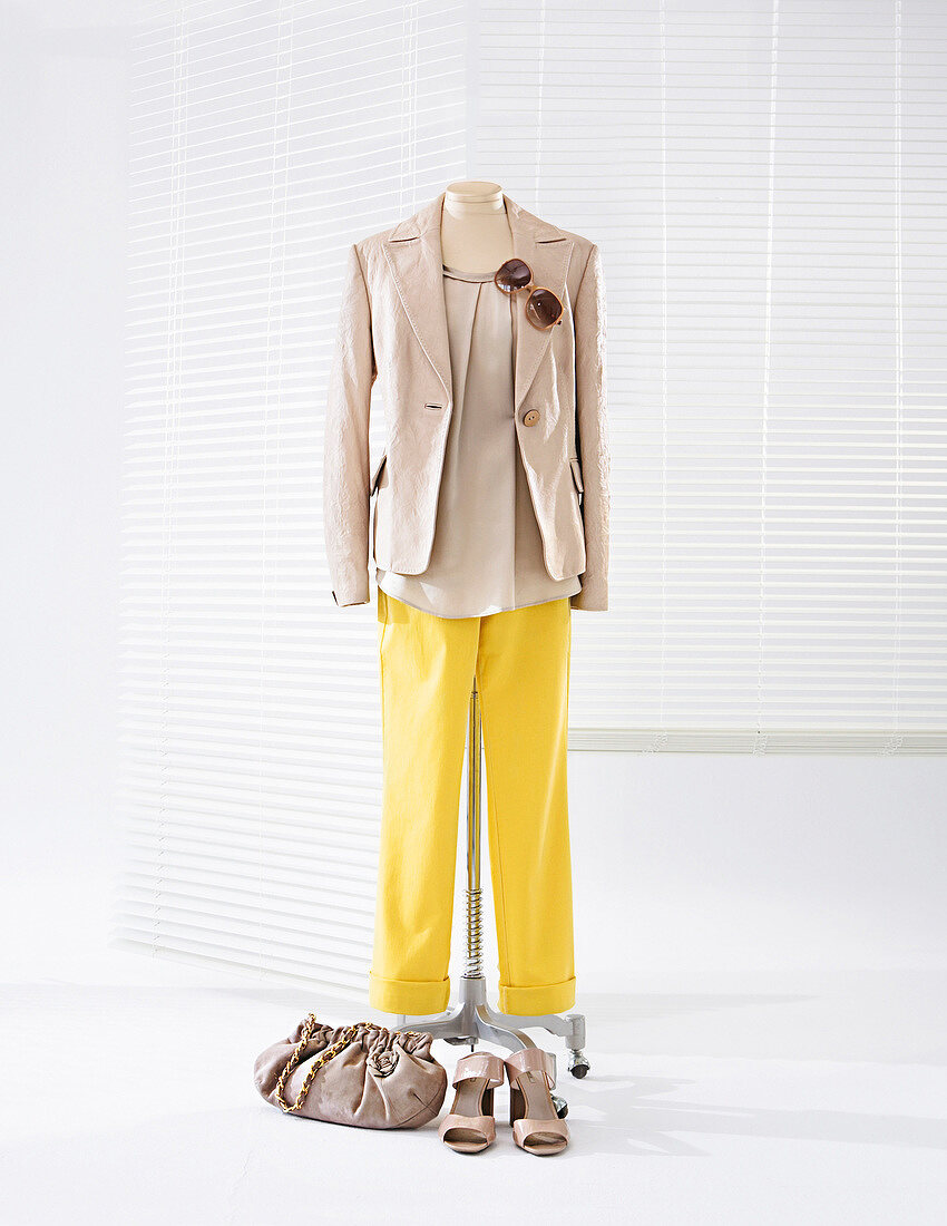 Satin blouse, leather jacket and yellow jeans on clothes stand