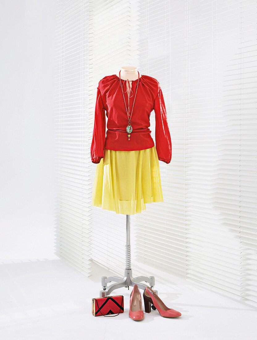 Red silk blouse and yellow skirt on clothes stand