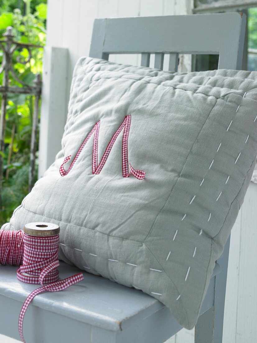 A homemade decorative cushion with an appliquéd letter