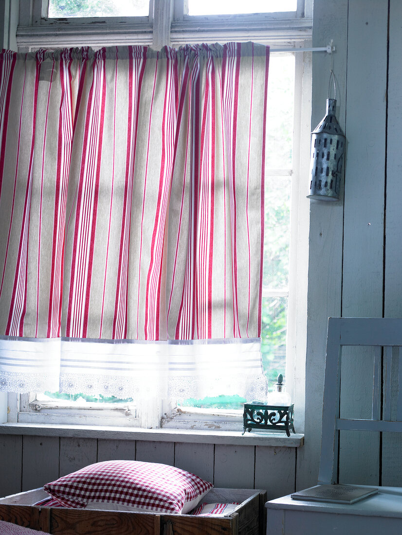 Red and white striped curtain with lingerie lace on window