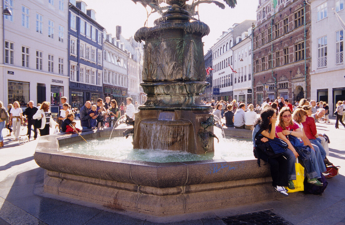 People sitting around Stork Fountain at Amager Torv square in Copenhagen, Denmark