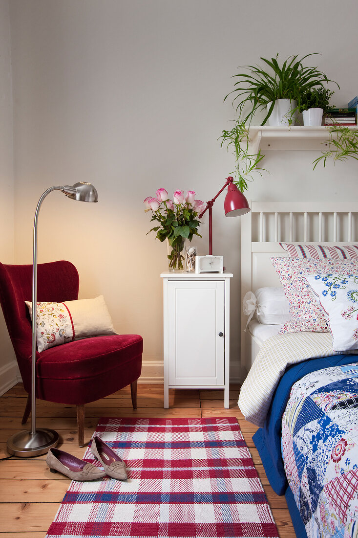 Red armchair with cushion, bedside table and bed