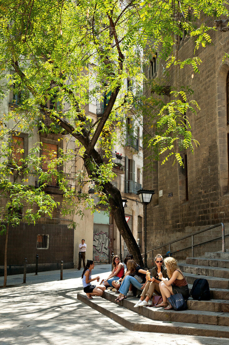 People sitting on stairs in alley, Barcelona, Spain