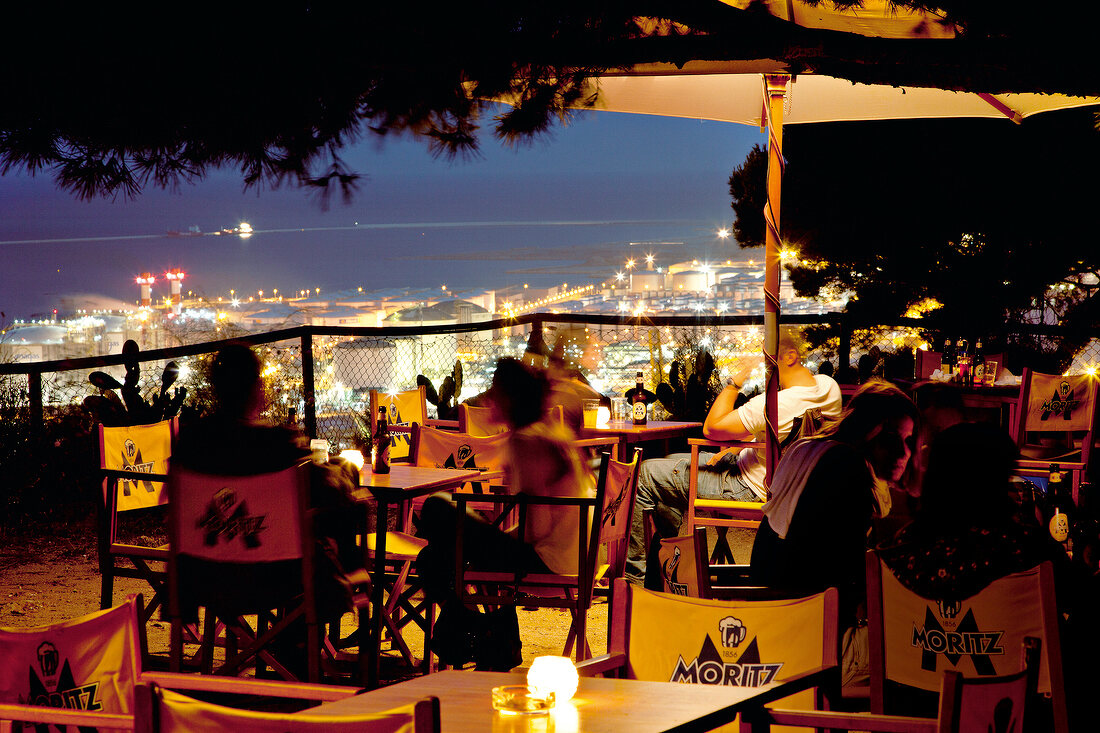 Guests sitting on terrace of La Caseta Club at night in Barcelona, Spain