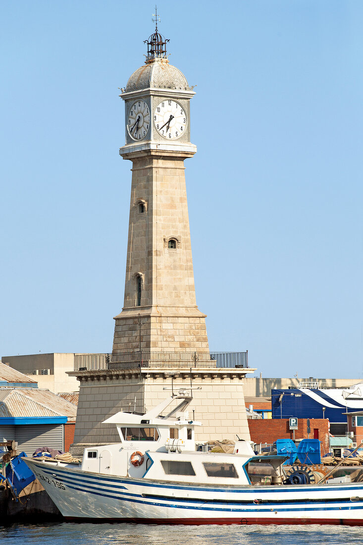 Boats moored at harbour in front of clock tower, Barcelona, Spain