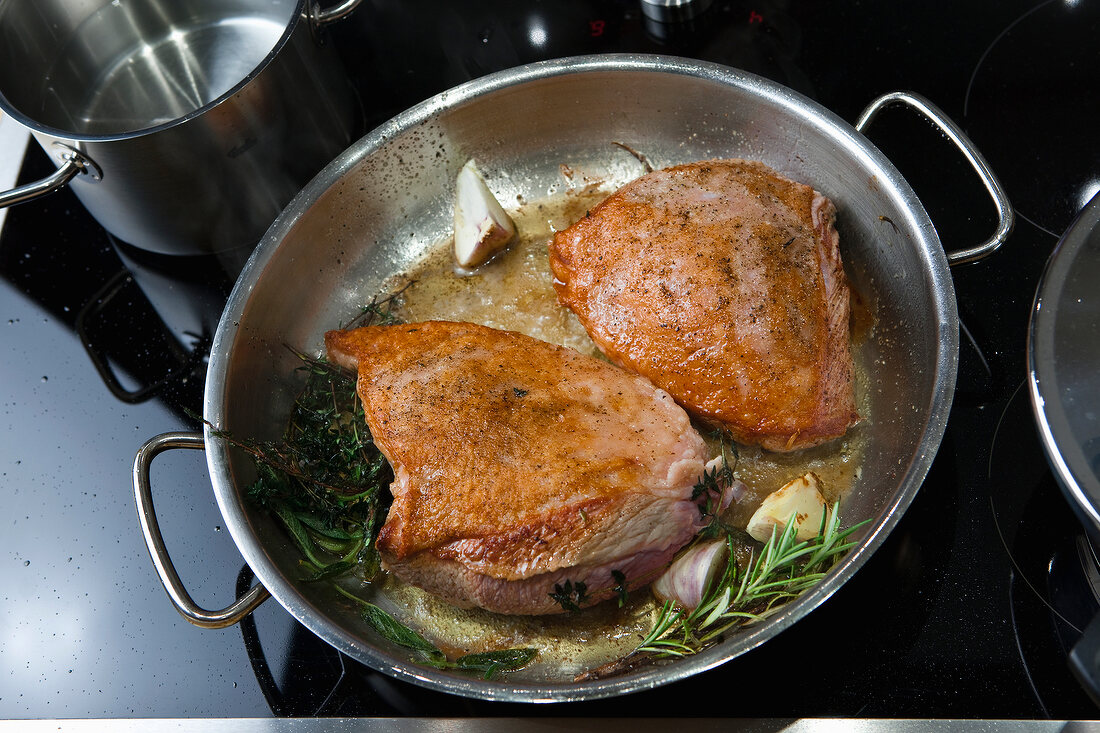 Veal is seared with herbs and garlic in pan