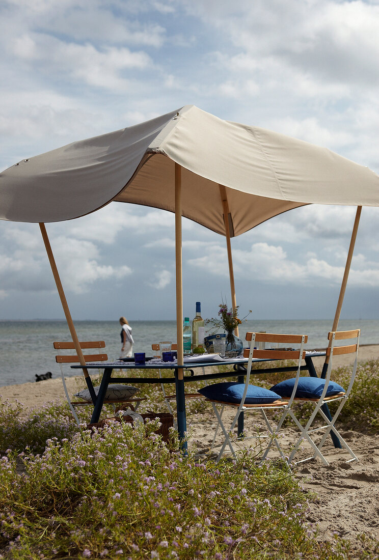 Outdoor-Möbel: Gartentisch mit aufge stecktem Sonnendach am Strand