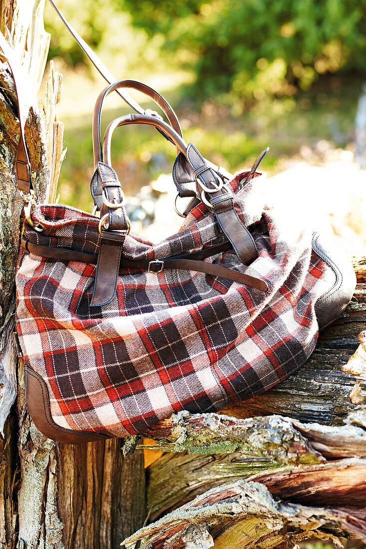 Close-up of red and black checked pattern bag on wood