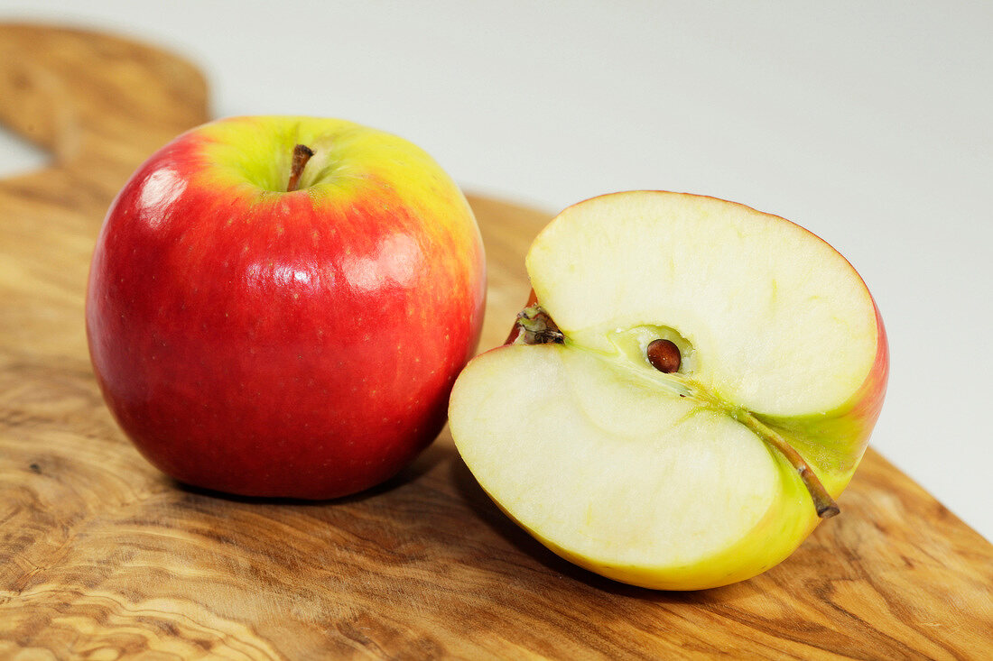 Close-up of whole and halved apple on wooden board