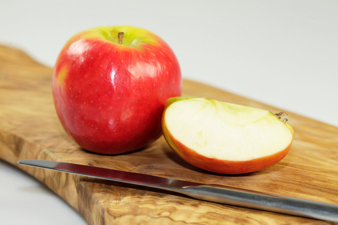 Close-up of whole and halved apple on wooden board