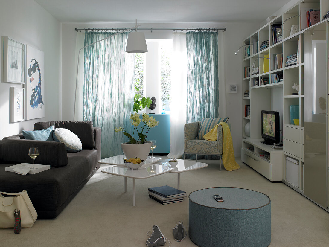 View of living room with black sofa, glass table, arm chair and bookshelf