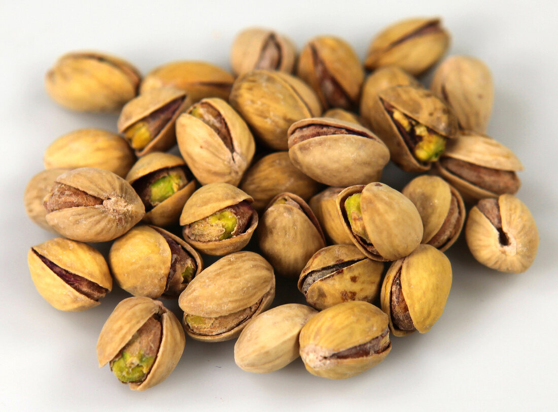 Pistachios in broken shells on white background