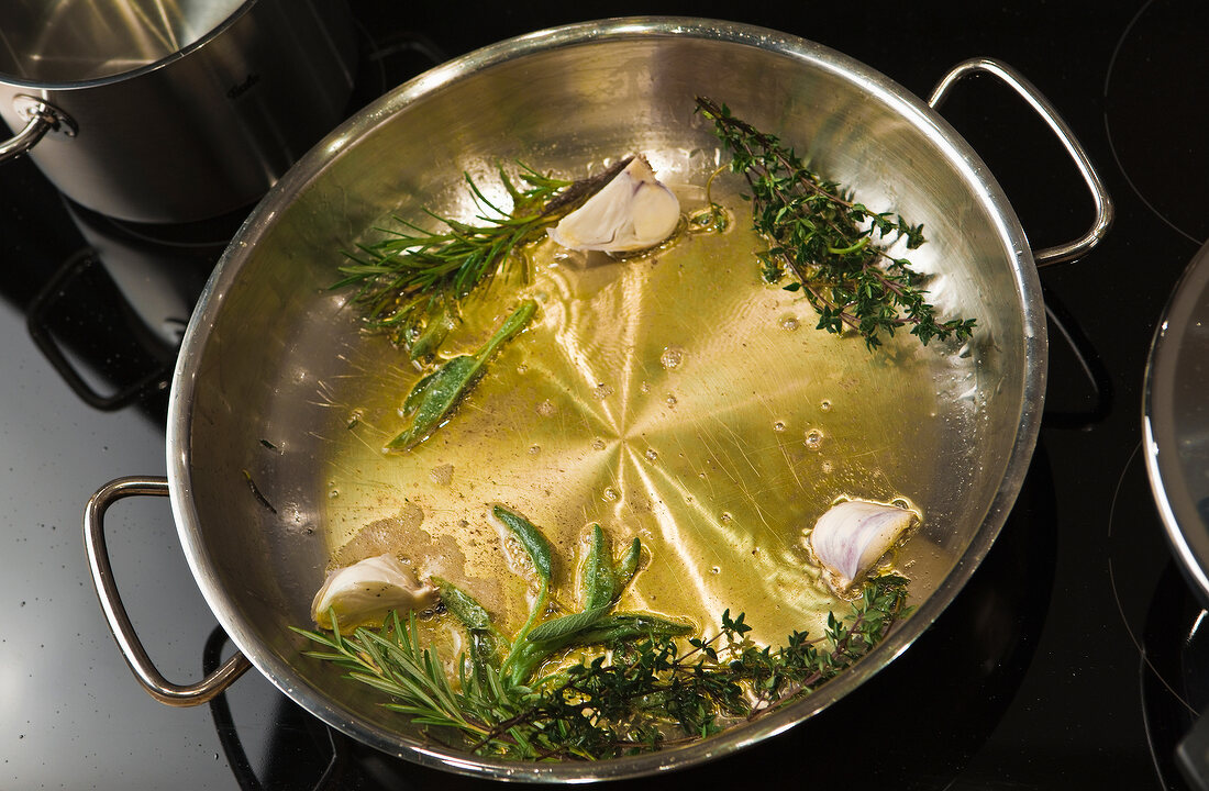 Fresh herbs, butter and olive oil in pan for preparation of veal