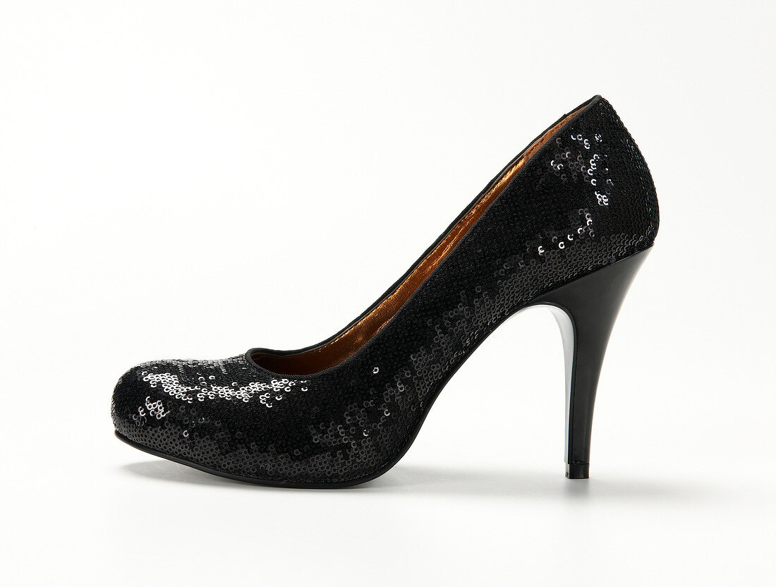 Close-up of black platform pumps with sequins on white background
