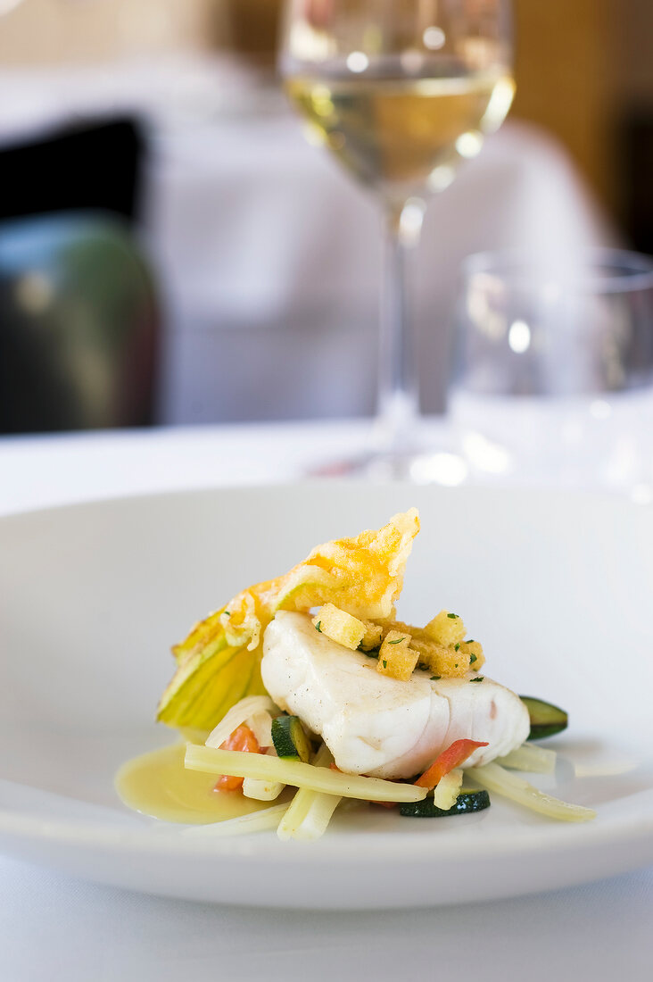 Close-up of sea bass with tomato, zucchini, basil and herb crust on dish