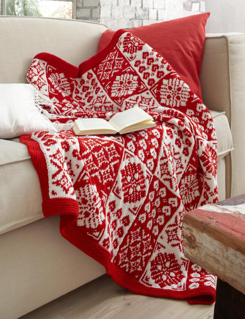 Red and white knitted blanket on sofa with book