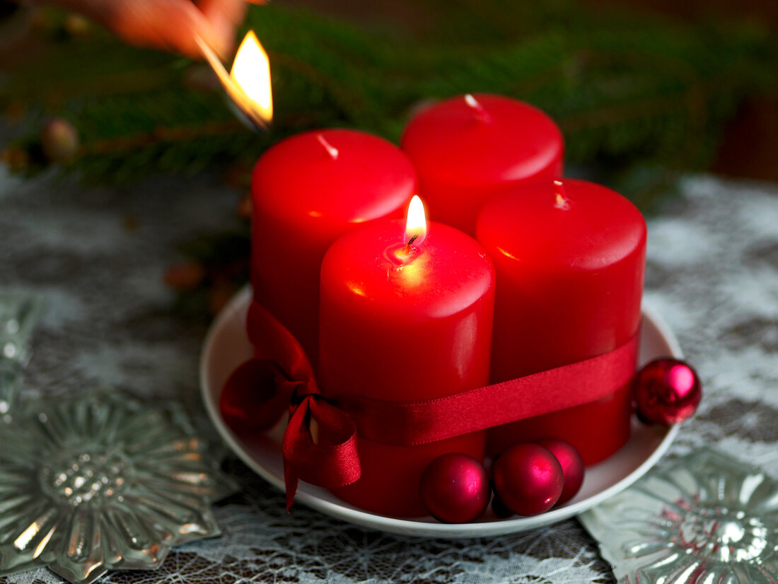 Four red candles on plate being lit for Advent