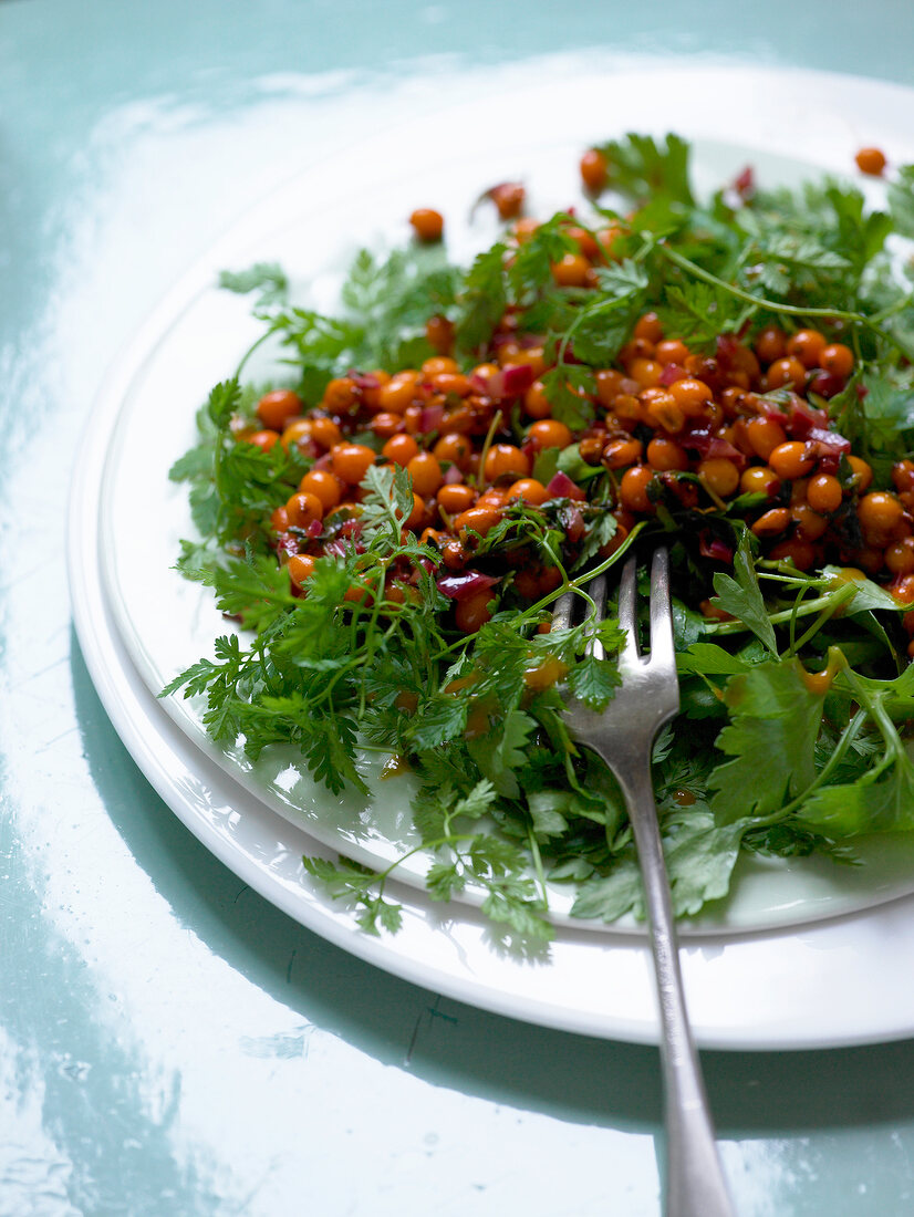 Close-up of herb salad with caramelized sea buckthorn on plate