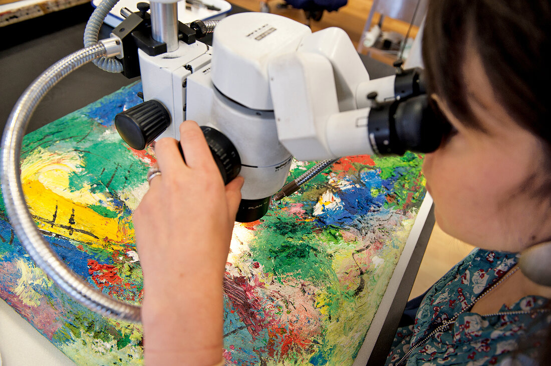 Woman looking at paintings through microscope in The Museum of Modern Art, New York, USA