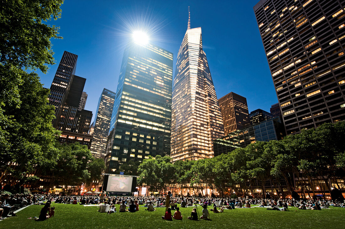 People sitting in meadow and watching movie at Bryant Park, New York, USA