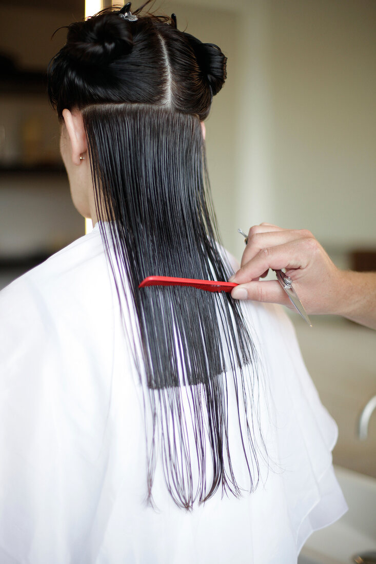 Rear view of woman with long hair getting hair cut